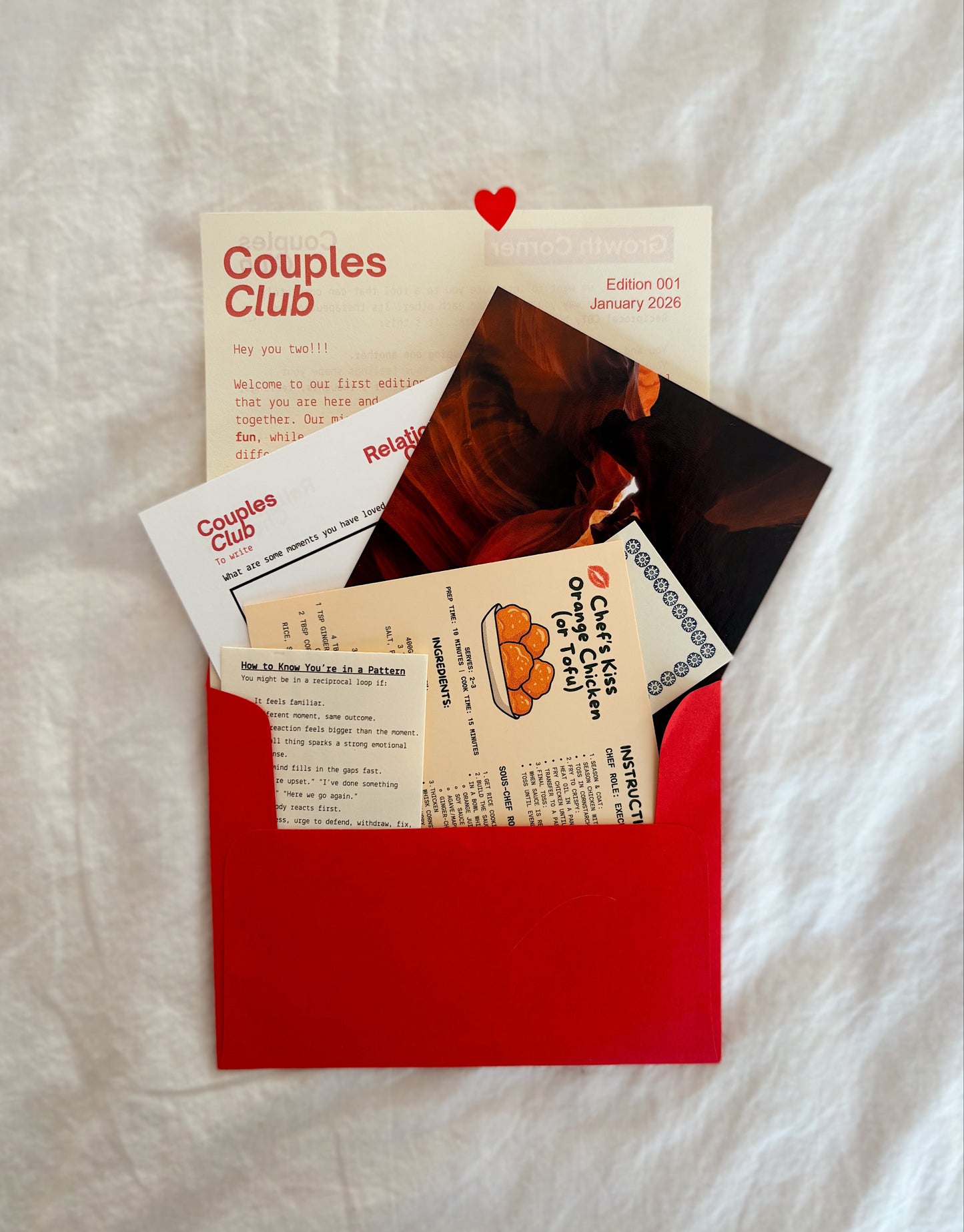 Red envelope with 'Couples Club' materials on a textured white surface